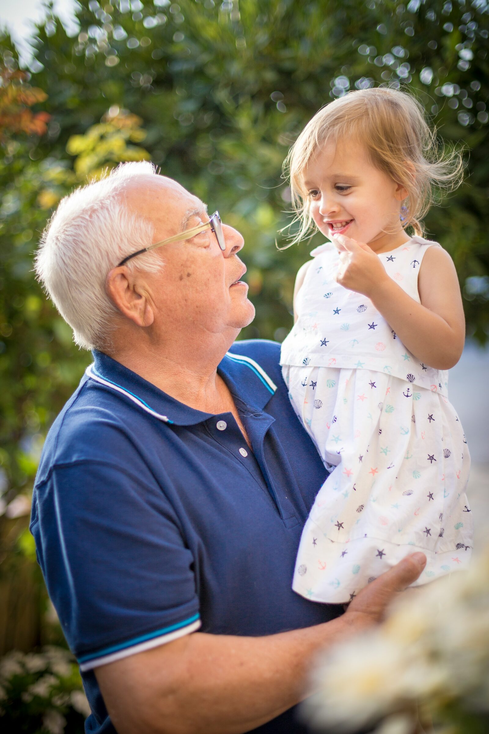 Un abuelo con su nieta a upa, en el jardín