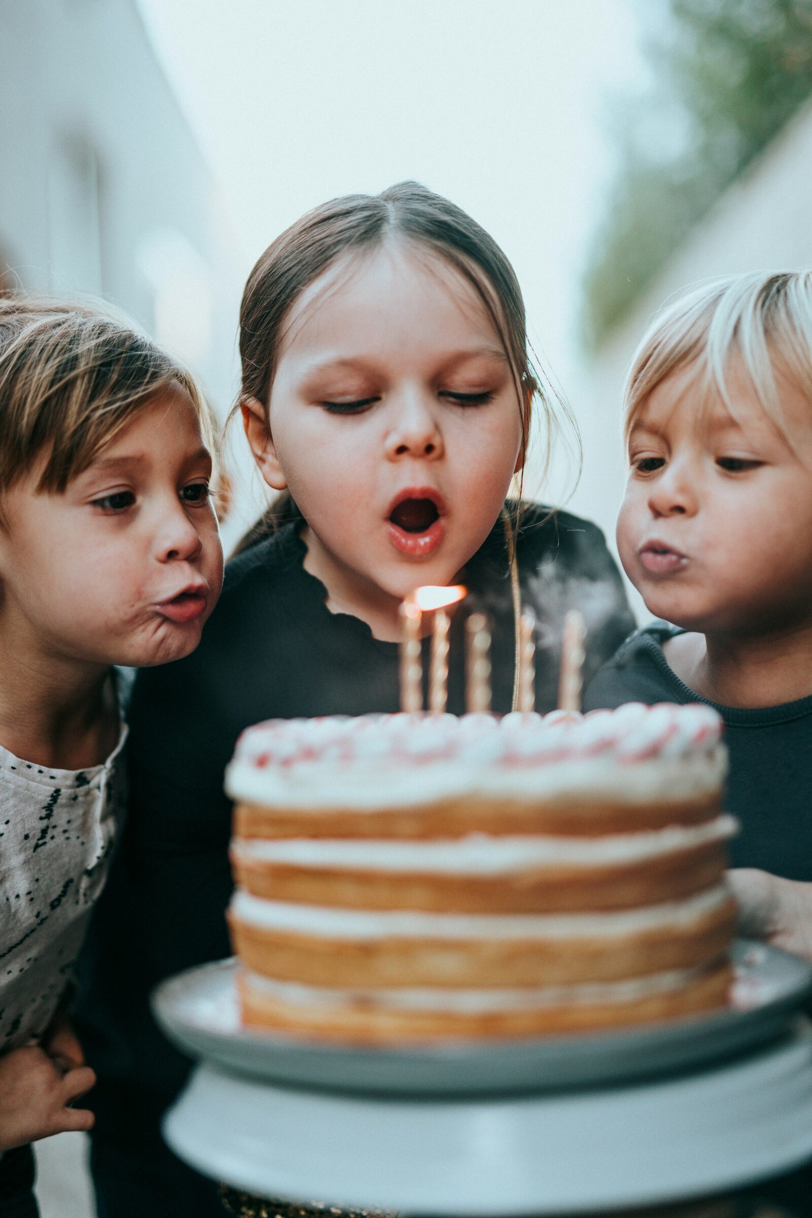 Tres chicos soplando las velitas de una torta
